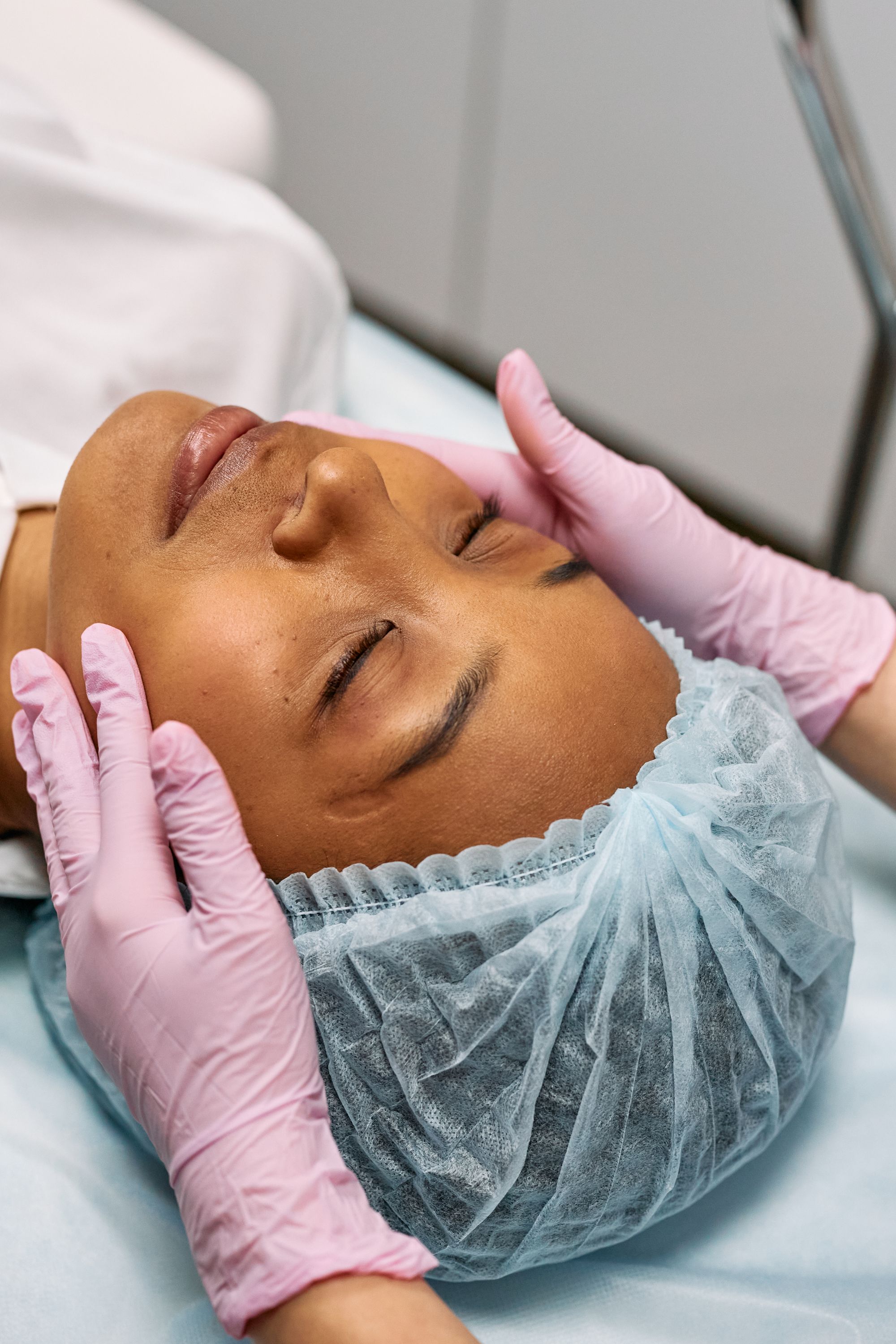 Close-up of a client receiving a gentle professional facial massage with gloved hands.