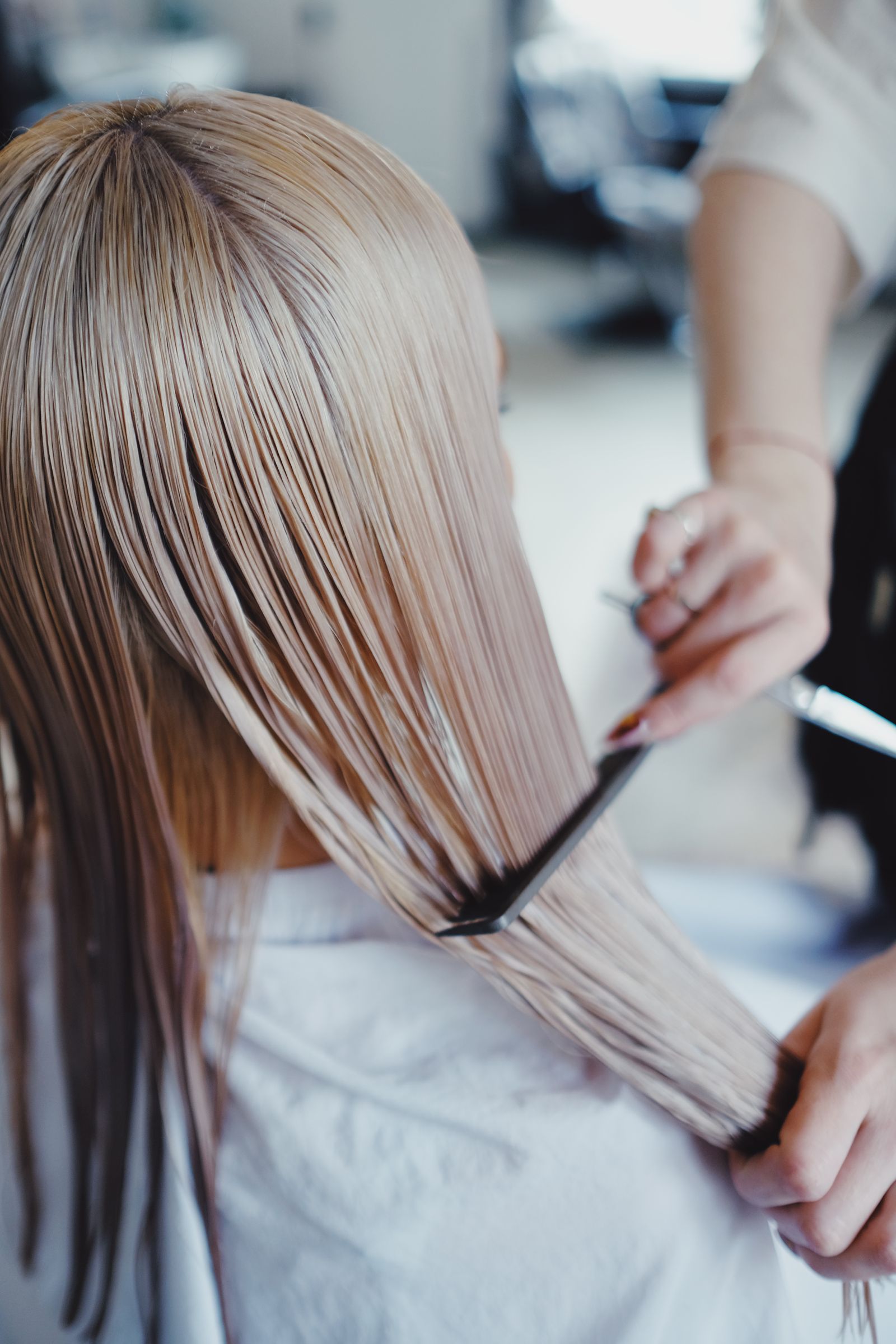 Hairdresser combing long blonde hair during a salon service